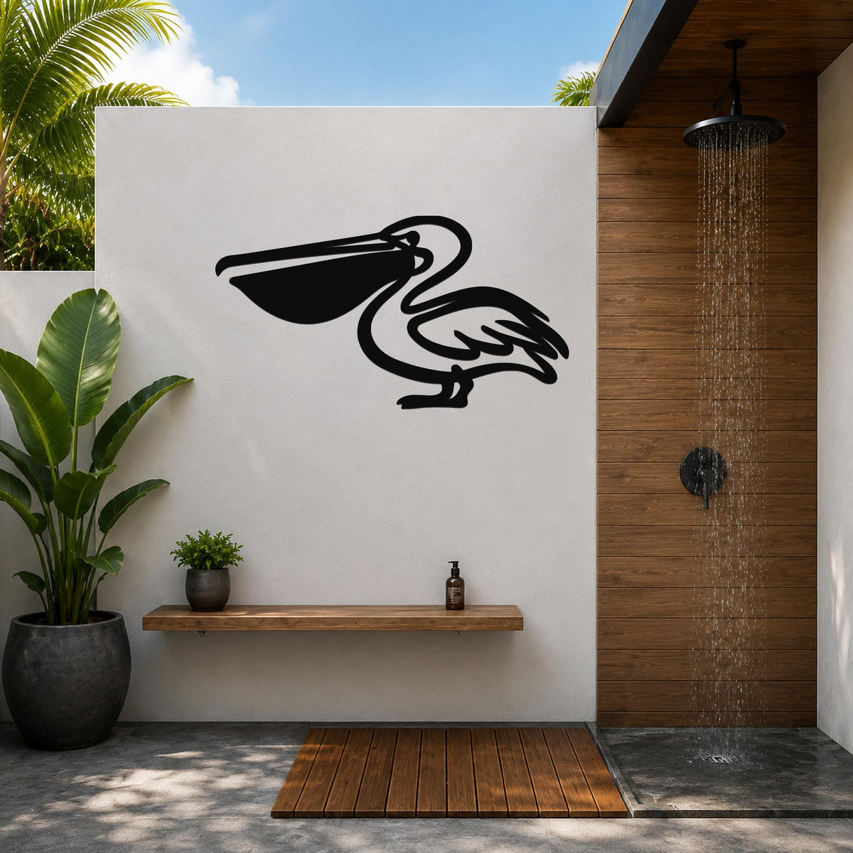 Black metal pelican wall art silhouette mounted on a white outdoor wall above a wooden shelf in a tropical shower area.