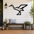Black metal crane wall art silhouette mounted on a white shiplap wall above a wooden bench on a porch.