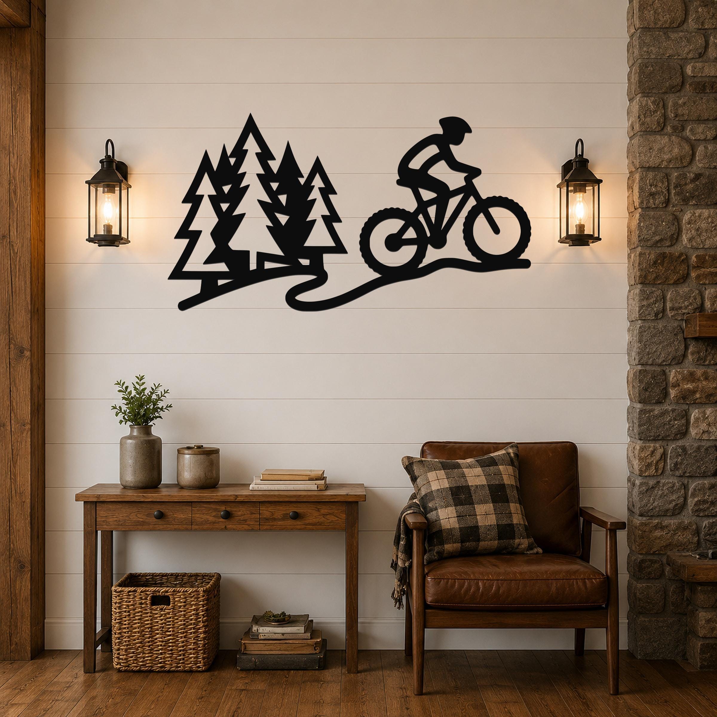 Black metal wall art cutout of a cyclist on a trail with pine trees, mounted on a shiplap wall above a wooden console table in a living room.