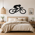 Black metal wall art featuring a cyclist silhouette in motion, mounted above a bed in a neutral bedroom.