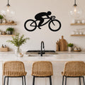 Black metal cycling wall art silhouette of a rider on a bike, mounted above a kitchen counter with open shelves and pendant lights.