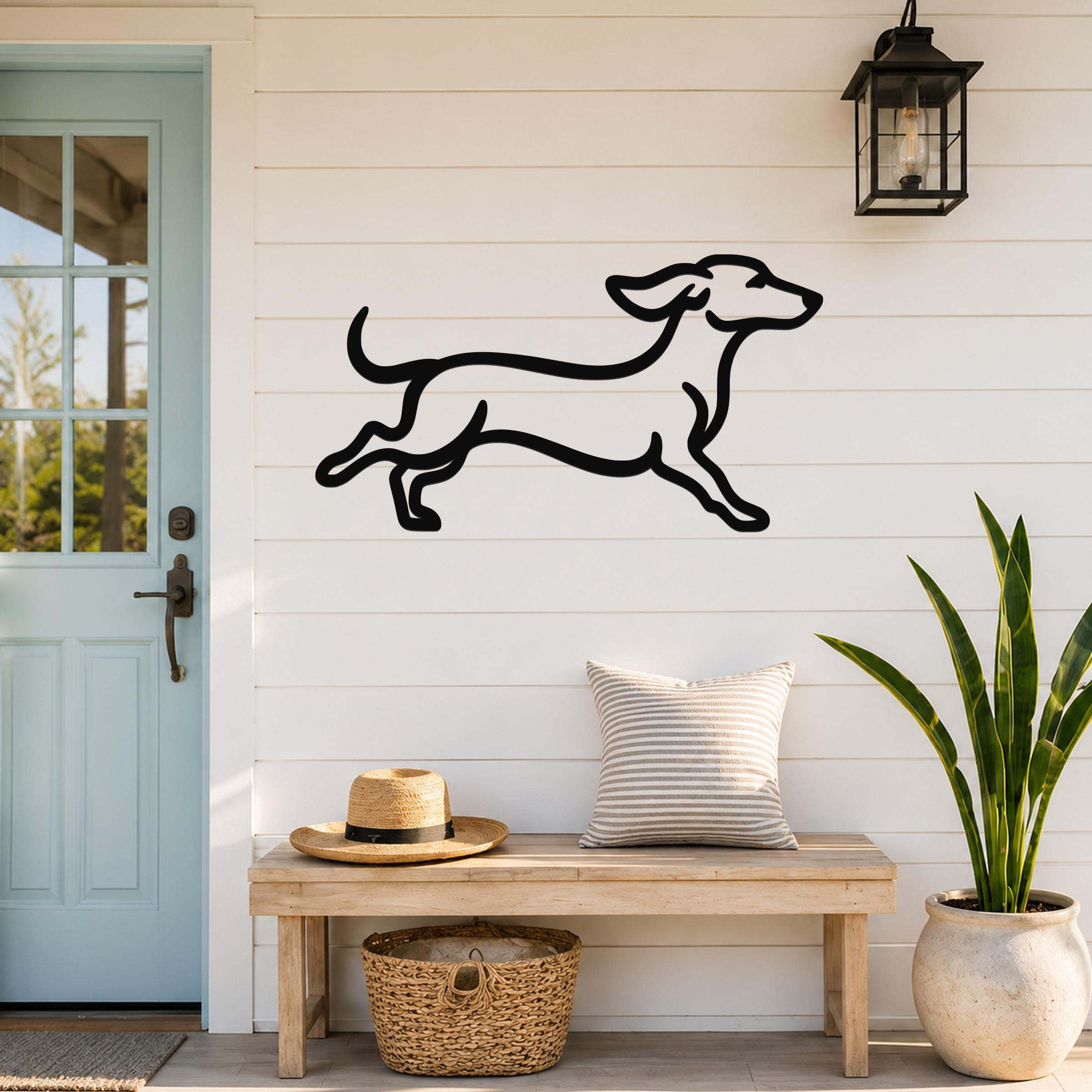 Black metal dachshund wall art with a playful running silhouette, mounted on a white shiplap wall above a wooden bench in a front entryway.
