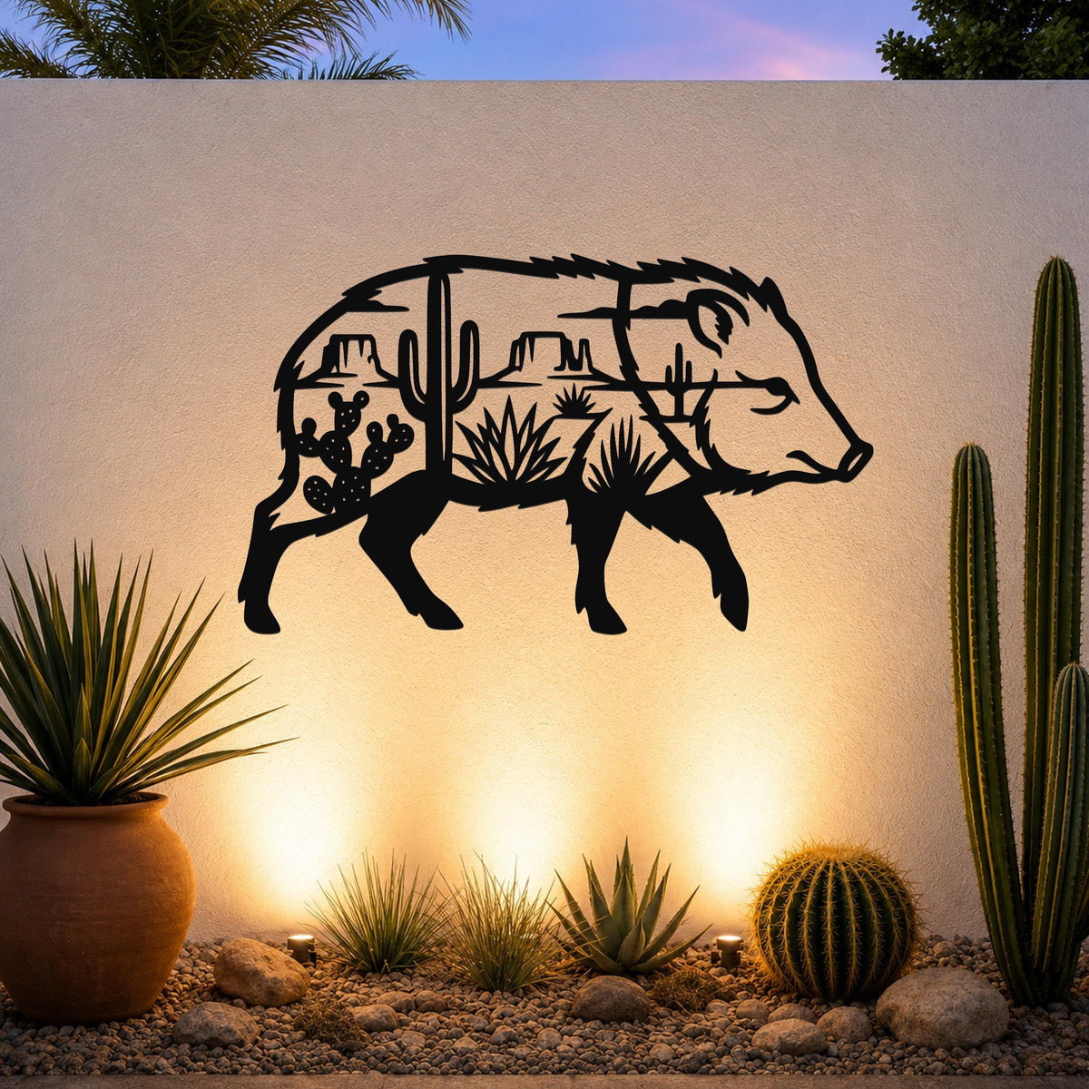 Black metal wall art of a javelina silhouette with desert cacti and rock formations cut out inside, mounted on an outdoor wall above a gravel garden with potted succulents and cacti.