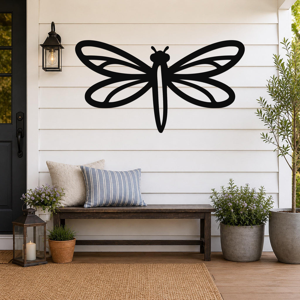 Black metal dragonfly wall art with detailed wing cutouts, mounted on a white shiplap wall above a wooden bench on a porch.