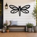 Black metal dragonfly wall art with detailed wing cutouts, mounted on a white shiplap wall above a wooden bench on a porch.