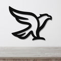 Black metal eagle wall art with a bold silhouette design, mounted on a white wall above a light wood surface.