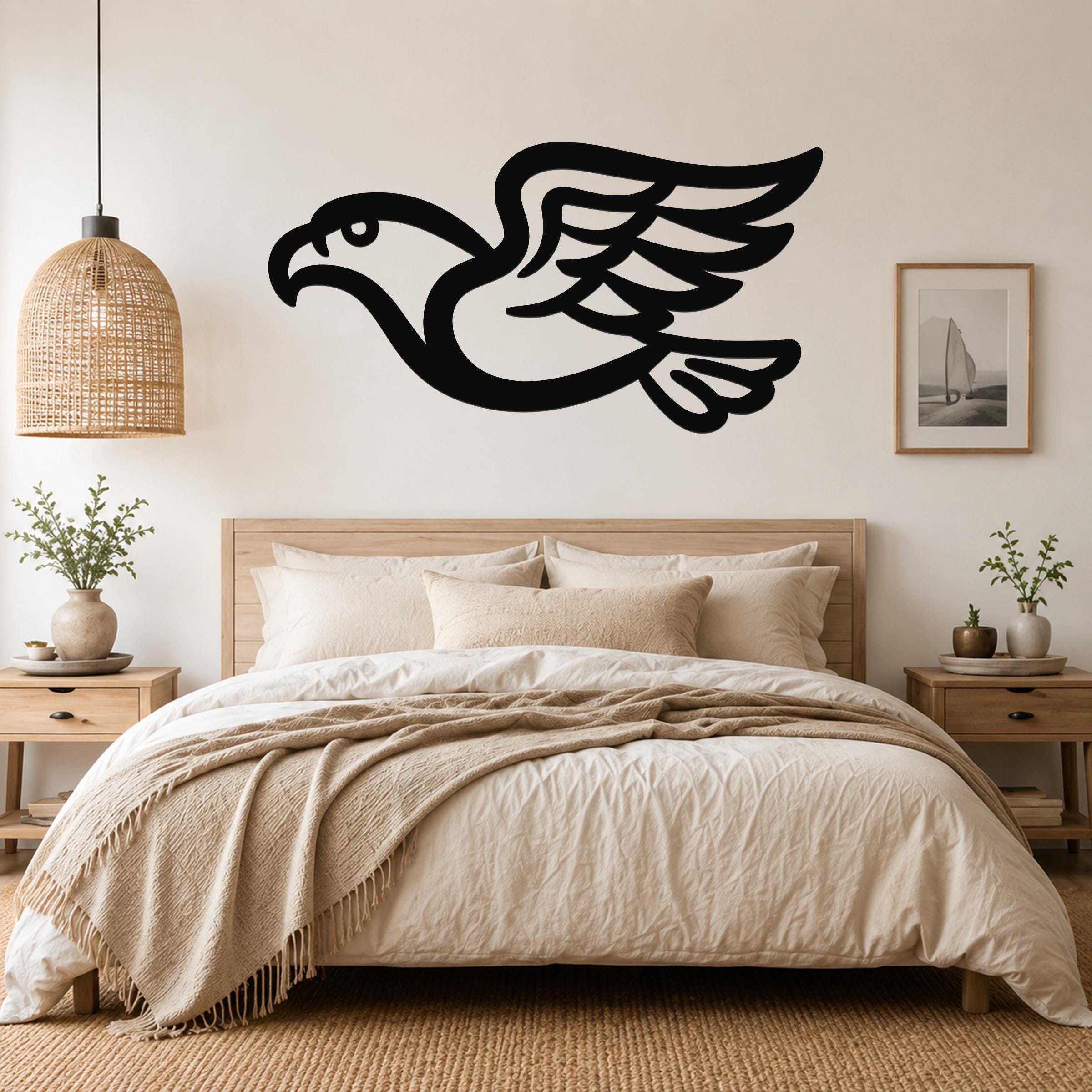 Black metal eagle wall art with a bold silhouette and detailed wing feathers, mounted above a wooden bed in a neutral bedroom.