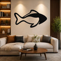 Black metal fish wall art with bold silhouette design, mounted on a living room wall above a beige sofa.