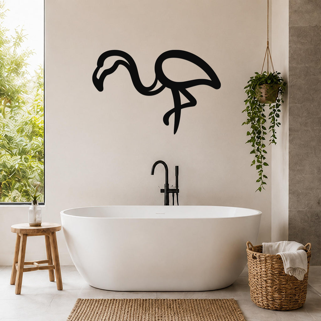 Black metal flamingo wall art silhouette mounted on a bathroom wall above a freestanding tub, with a hanging plant and woven basket nearby.