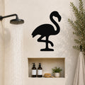 Black metal flamingo wall art silhouette mounted on a bathroom wall above a built-in shelf, with a shower head spraying water to the left.