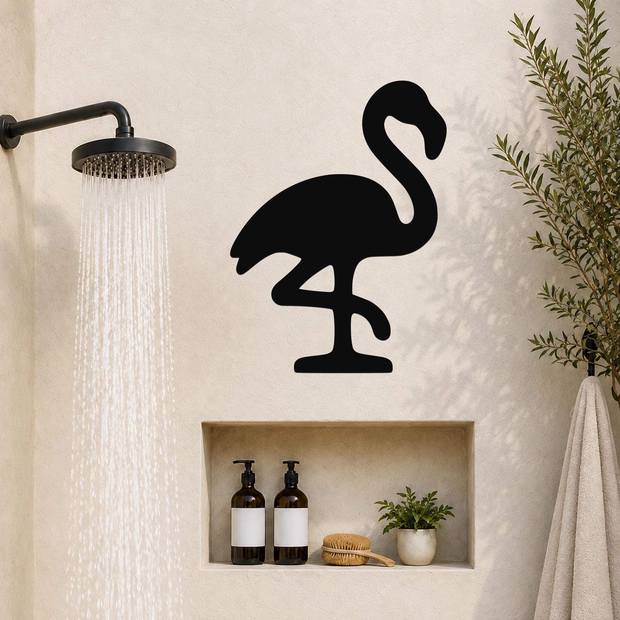 Black metal flamingo wall art silhouette mounted on a bathroom wall above a built-in shelf, with a shower head spraying water to the left.