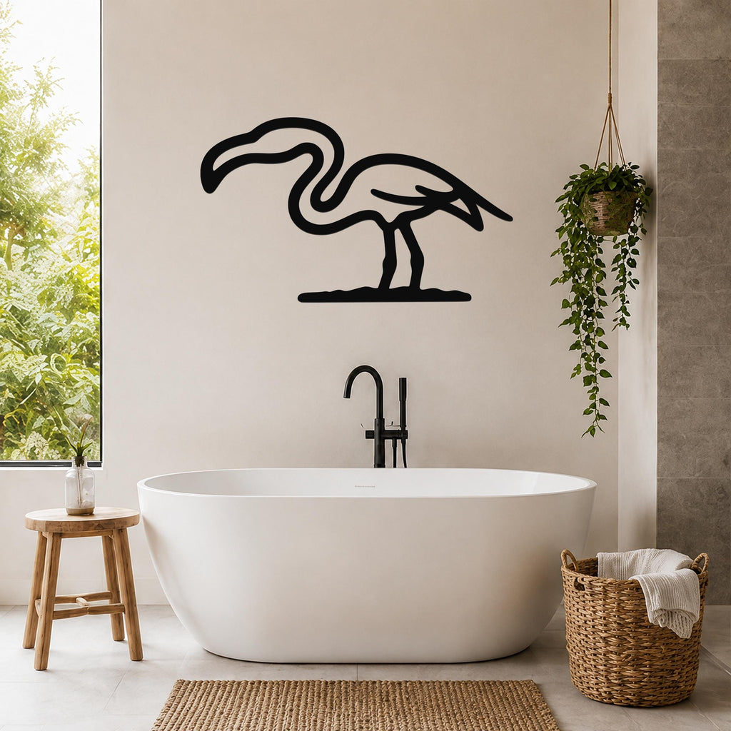 Black metal flamingo wall art silhouette mounted on a bathroom wall above a freestanding tub, with a hanging plant and woven basket nearby.