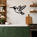 Black metal hummingbird wall art with motion-line cutouts, mounted on a tiled kitchen wall above a counter.