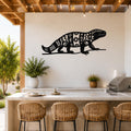 Black metal wall art of a Gila monster silhouette with intricate geometric and sun cutouts, mounted on a white wall above a kitchen counter.