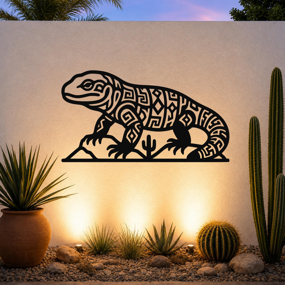 Black metal wall art of a Gila monster with intricate geometric cutouts, mounted on an outdoor wall above a desert garden with cacti and warm uplighting.