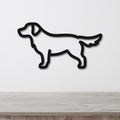 Black metal dog silhouette wall art in a golden retriever shape, mounted on a white wall above a light wood surface.