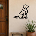 Black metal wall art in the silhouette of a sitting dog, mounted on a beige exterior wall beside a wooden door and a potted plant.