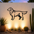 Black metal Golden Retriever wall art silhouette mounted on an outdoor wall above a desert garden with cacti and warm ground lighting.