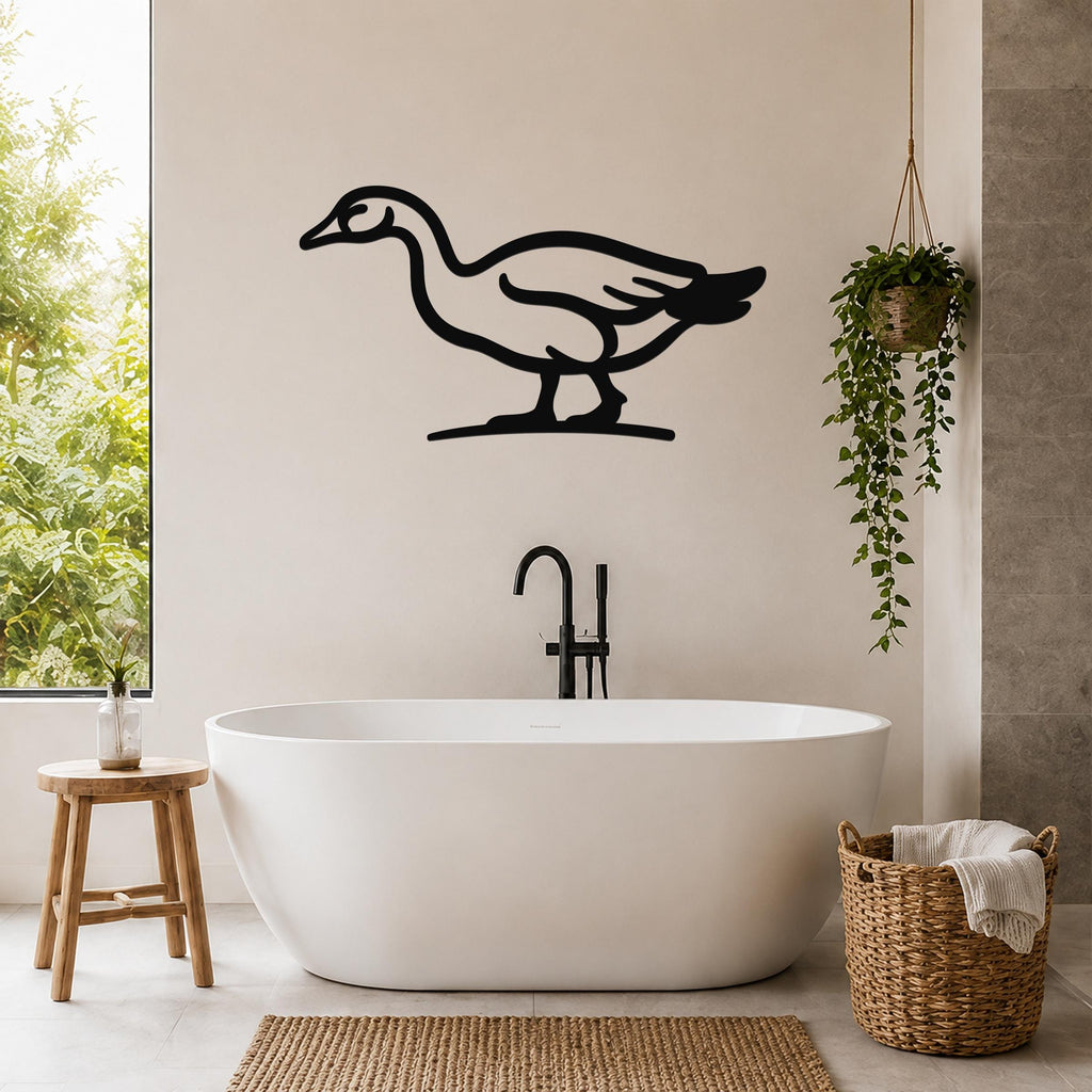 Black metal goose wall art silhouette mounted on a bathroom wall above a freestanding tub, with a hanging plant and woven basket nearby.