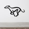 Black metal greyhound wall art with a minimalist silhouette design, mounted on a white wall above a light wood surface.