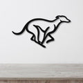 Black metal greyhound wall art with a sleek silhouette and internal cutout details, mounted on a white wall above a light wood surface.