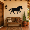 Black metal horse silhouette wall art mounted on a stucco wall above a wooden bench in a rustic patio entryway.