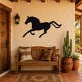 Black metal horse wall art silhouette with motion lines, mounted on a stucco wall above a wooden bench in a rustic patio entryway.