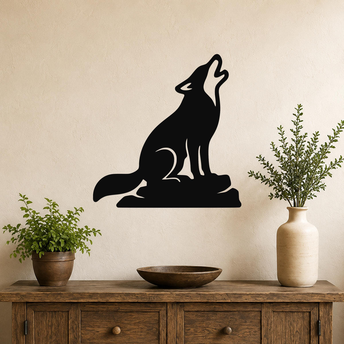 Black metal coyote wall art in a howling silhouette, mounted above a wooden console table with potted plants in a living room.