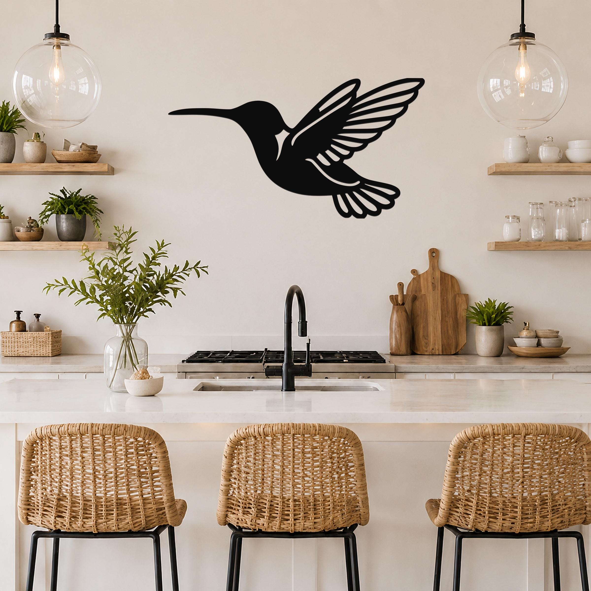 Black metal hummingbird wall art with wing and tail cutouts, mounted on a kitchen wall above a counter.