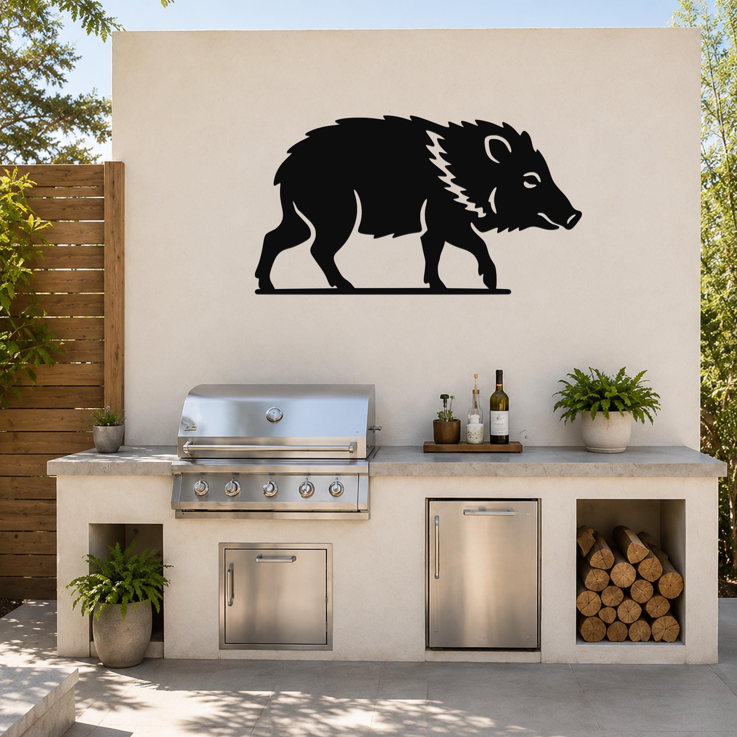 Black metal javelina wall art silhouette with internal cutout details, mounted on an outdoor patio wall above a stainless steel grill and countertop.
