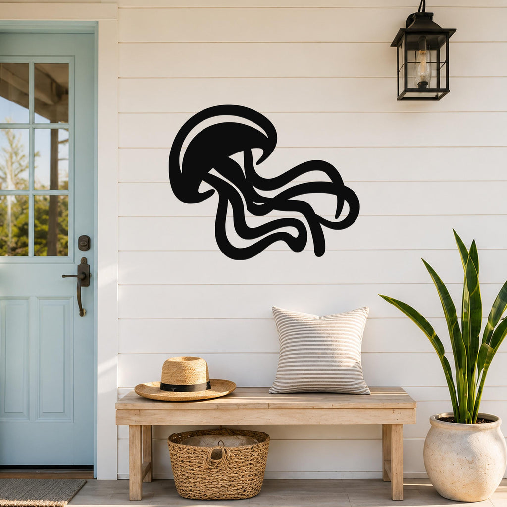 Black metal jellyfish wall art with flowing tentacle cutouts, mounted on a white shiplap wall above a wooden bench in a coastal entryway.