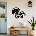 Black metal jellyfish wall art with flowing tentacle cutouts, mounted on a white shiplap wall above a wooden bench in a coastal entryway.