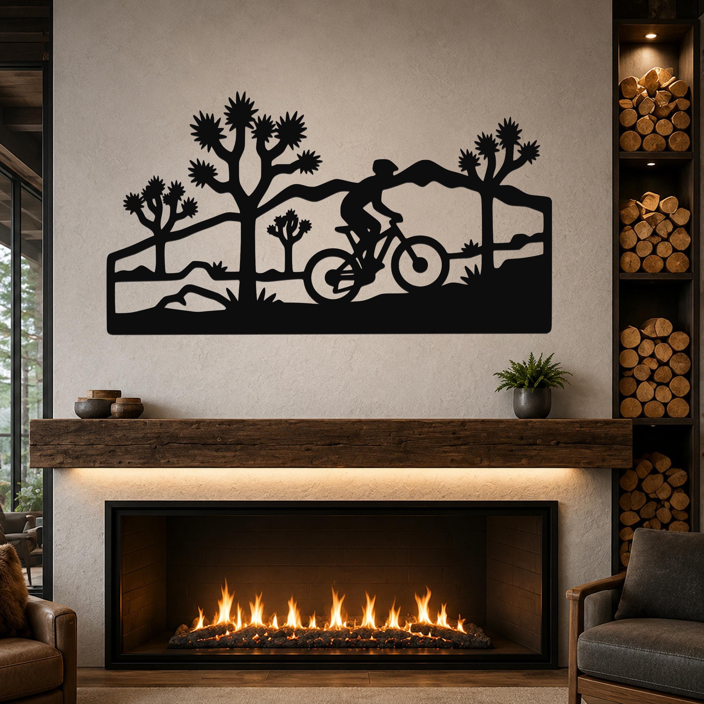 Black metal wall art with a silhouette of a cyclist and Joshua trees, mounted above a fireplace in a living room.