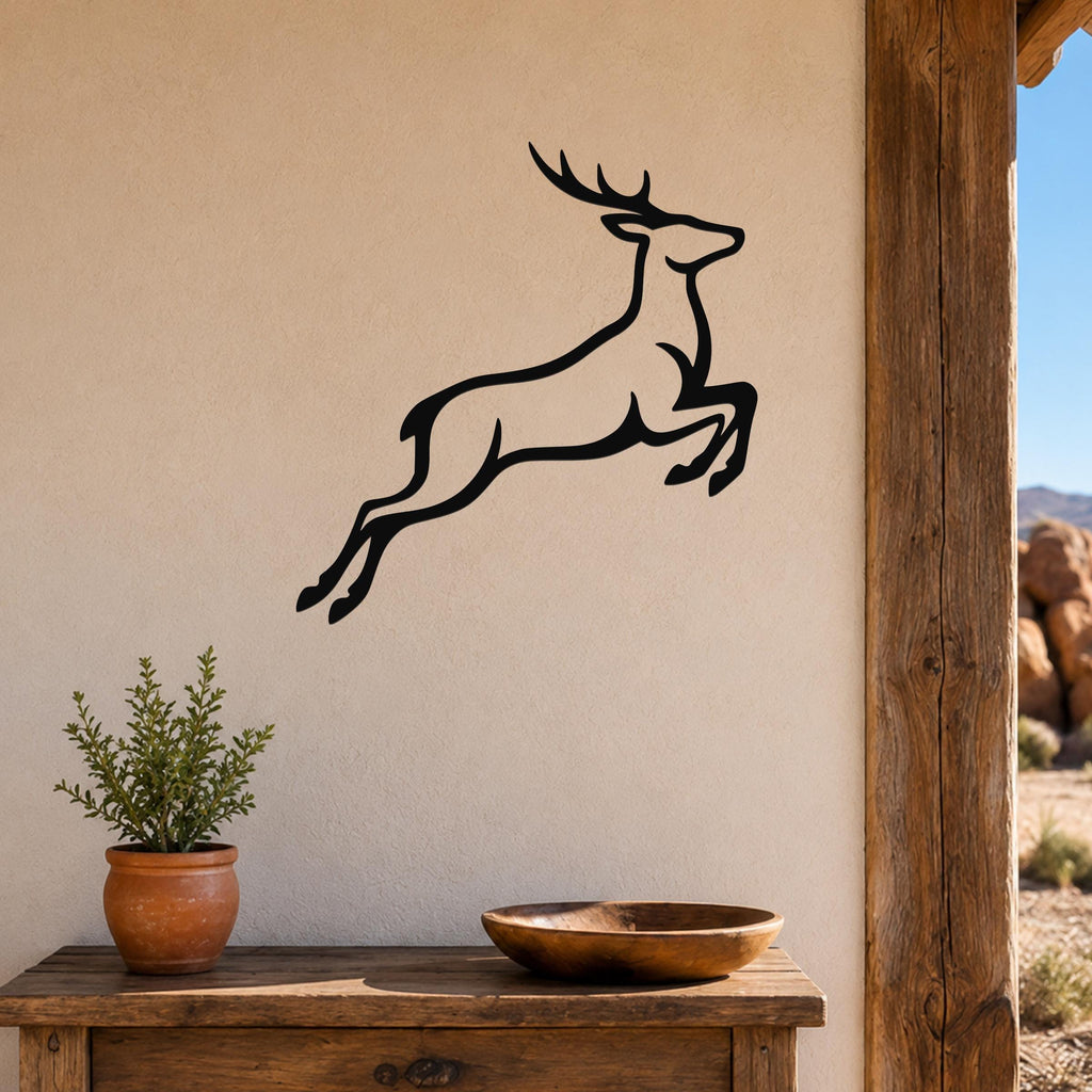 Black metal jumping deer wall art with motion-line cutouts, mounted on a beige wall above a wooden table in a rustic outdoor entryway.