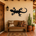 Black metal lizard wall art silhouette mounted on a stucco wall above a wooden bench in a rustic patio entryway.