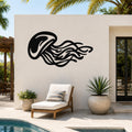 Black metal jellyfish wall art with flowing tentacle cutouts, mounted on a white outdoor wall beside a pool and lounge chair.
