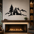 Black metal wall art with a mountain cabin and pine tree silhouette, mounted above a fireplace in a living room.