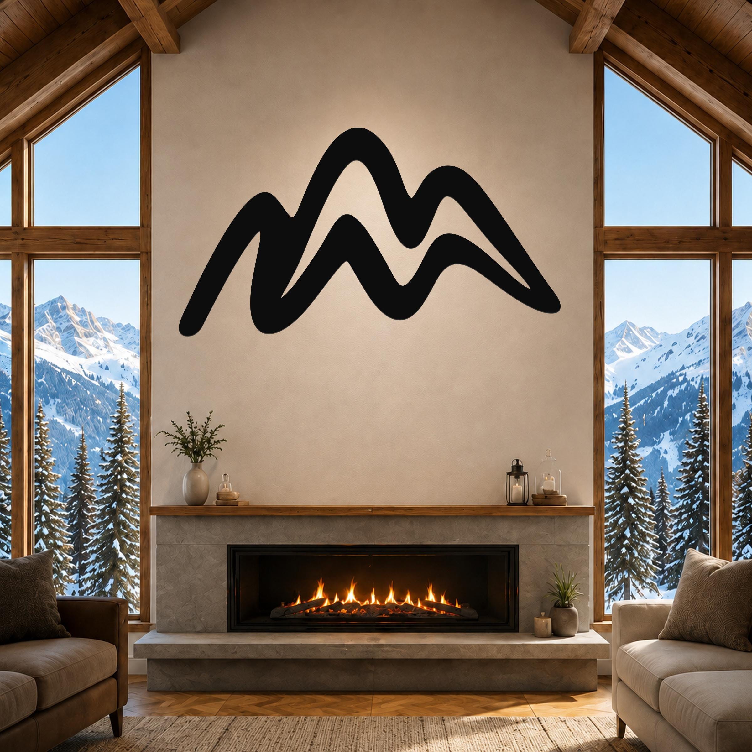 Black metal mountain silhouette wall art mounted above a fireplace in a rustic living room with large windows overlooking snowy peaks.