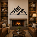 Black metal mountain silhouette wall art with jagged peaks, mounted above a stone fireplace in a rustic living room.