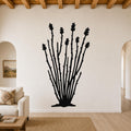 Black metal ocotillo wall art with branching stems and flower cutouts, mounted on a living room wall above a sofa.
