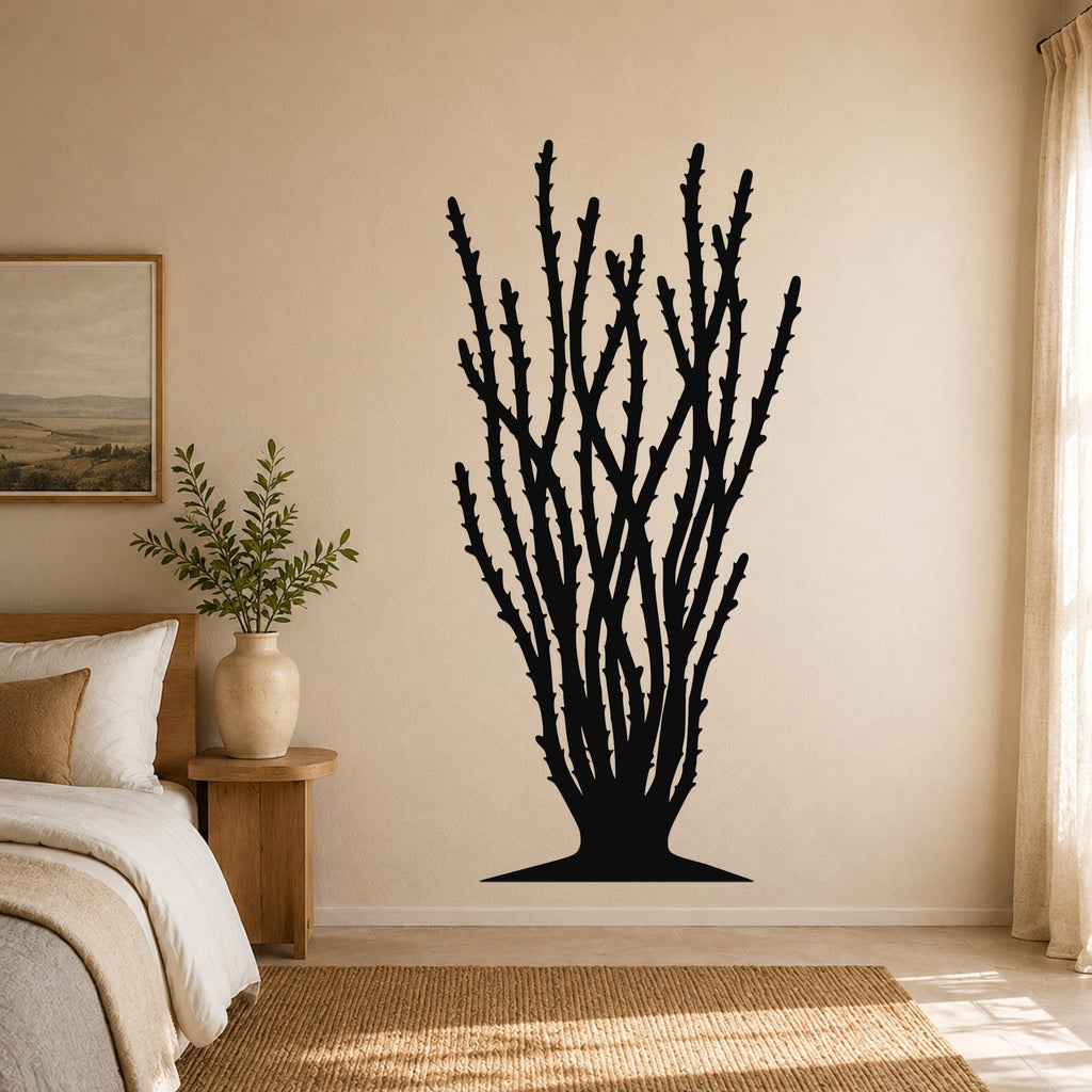 Black metal ocotillo wall art with spiny branch cutouts, mounted on a beige bedroom wall above a bed.