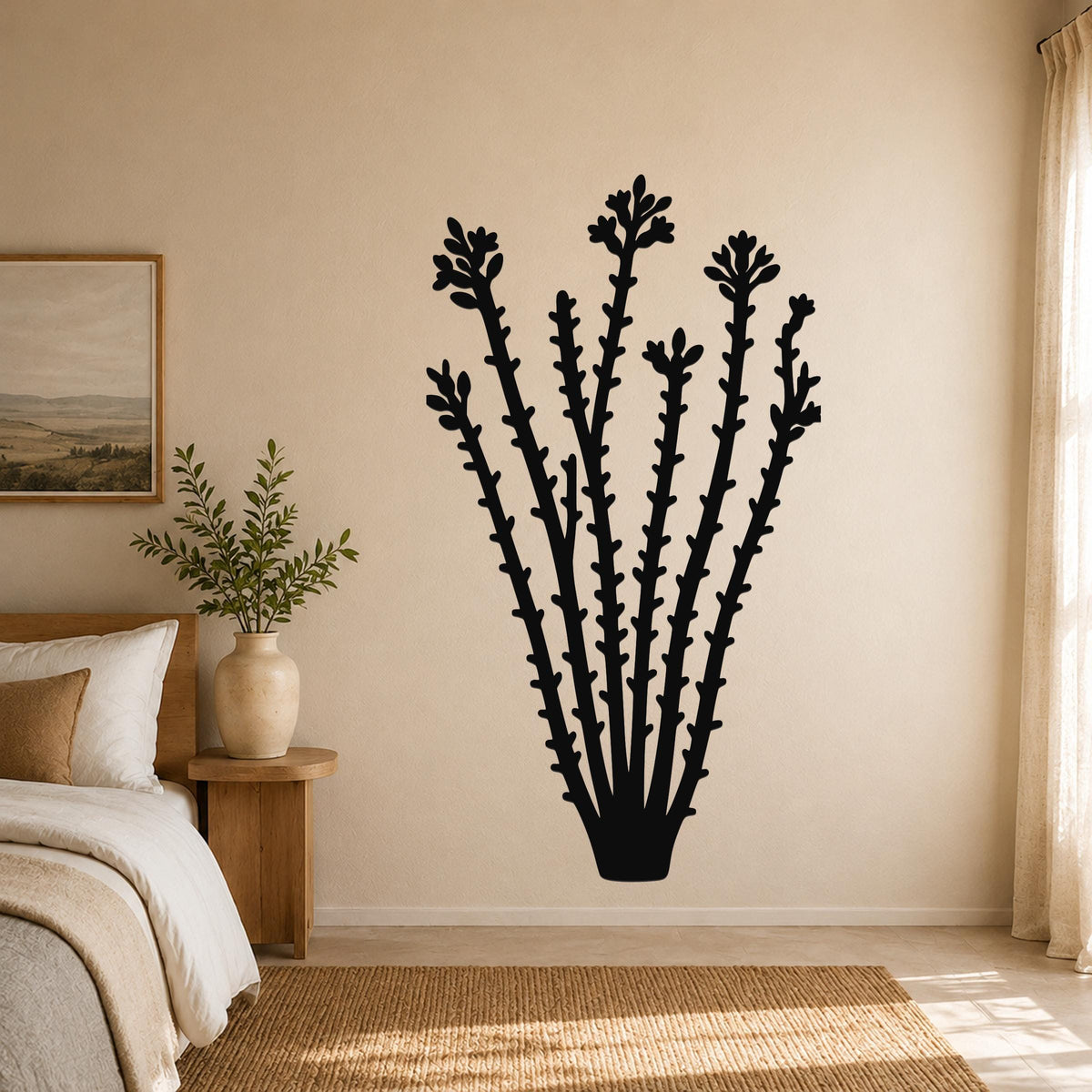 Black metal ocotillo wall art with flower and branch cutouts, mounted on a beige bedroom wall above a bed.