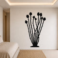 Black metal ocotillo wall art with flower and branch cutouts, mounted on a bedroom wall above a bed.