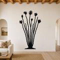 Black metal ocotillo wall sculpture with spiny stems and flower cutouts, mounted on a living room wall above a sofa.