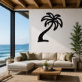Black metal palm tree wall art with a silhouette design, mounted on a white wall above a beige sectional sofa in a living room with ocean views.