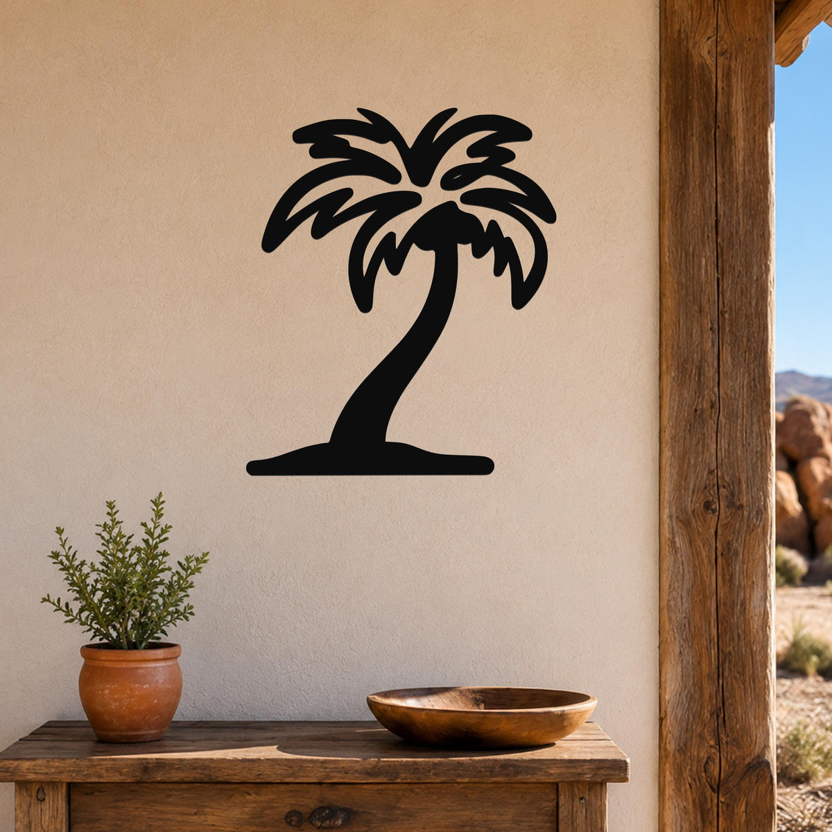 Black metal palm tree wall art with a silhouette design, mounted on a beige wall above a wooden table in a patio setting.