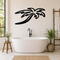Black metal palm tree wall art with flowing frond cutouts, mounted on a bathroom wall above a freestanding tub.