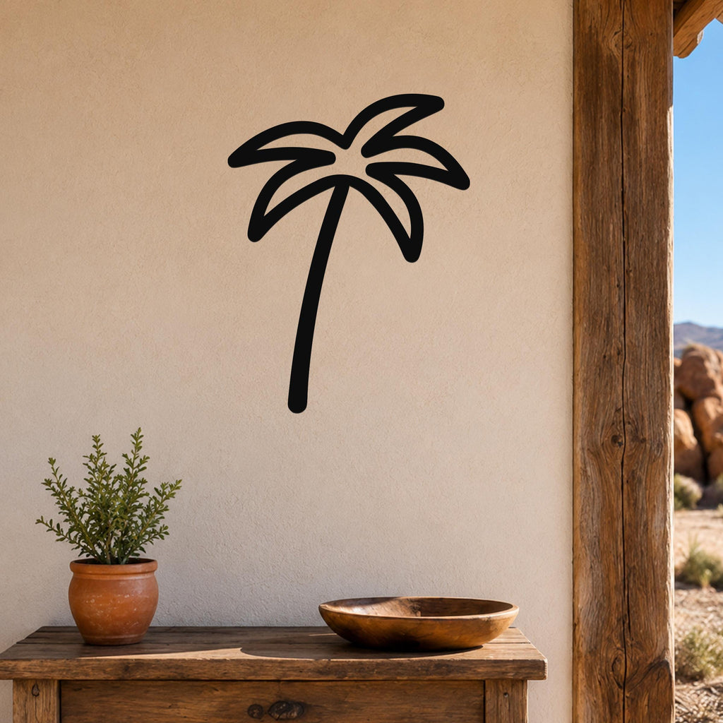 Black metal palm tree wall art with a silhouette design, mounted on a beige wall above a wooden table in a patio setting.