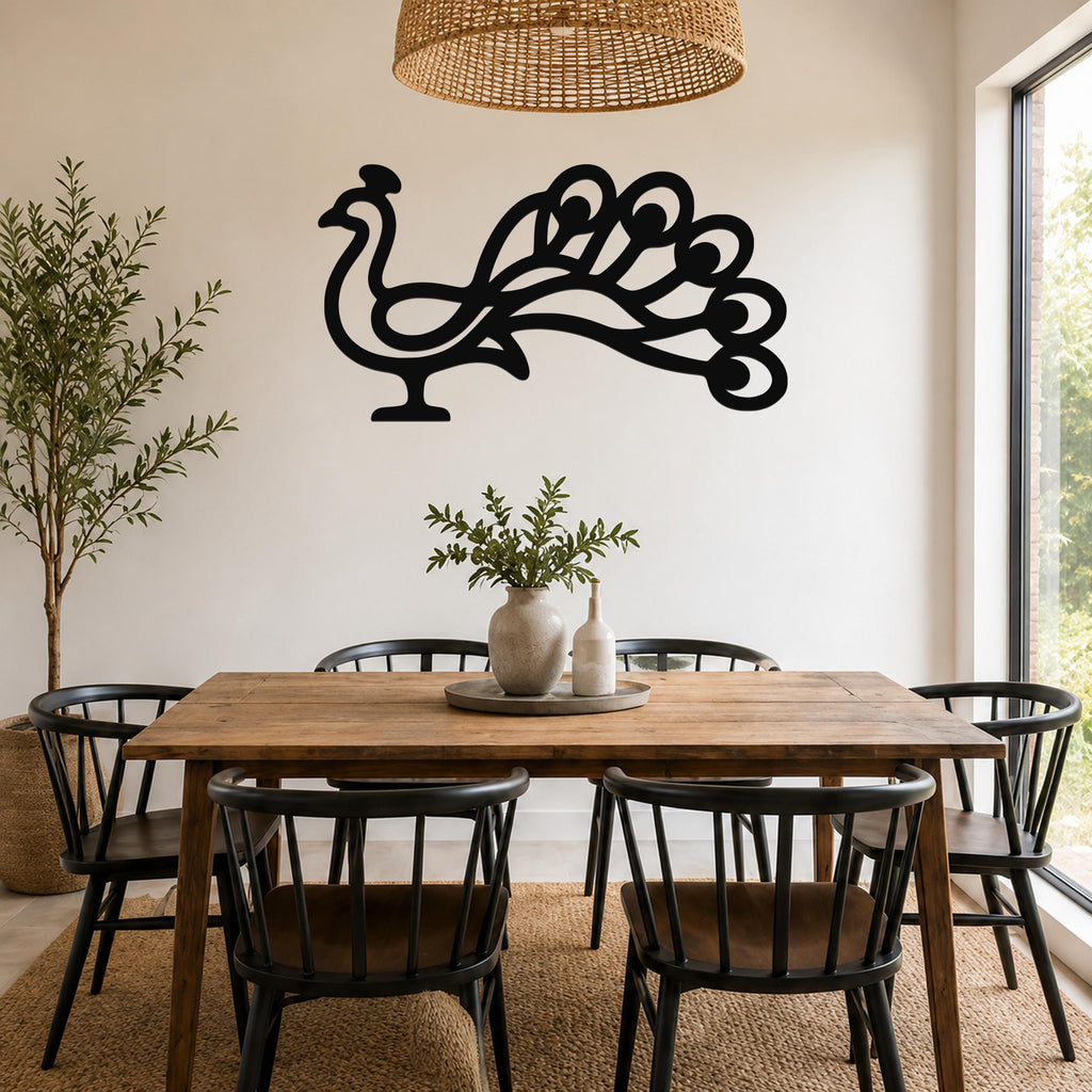 Black metal peacock wall art with a cutout silhouette of a fanned tail, mounted on a white wall above a wooden dining table in a bright dining room.