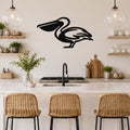 Black metal pelican wall art with a silhouette cutout, mounted on a kitchen wall above a counter with wicker bar stools.
